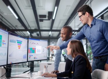 Profissionais a analisar ferramentas da qualidade em monitores.