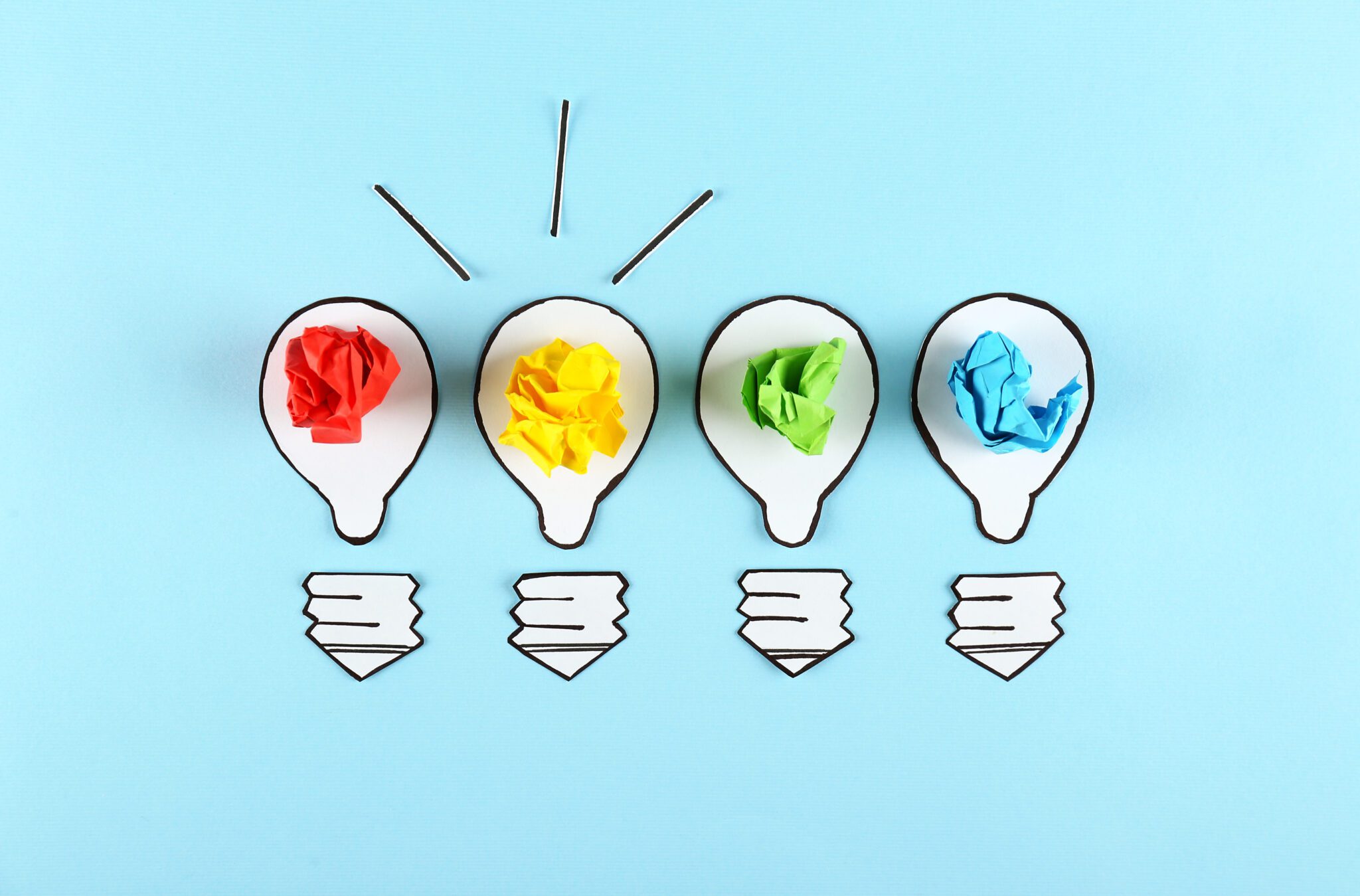 Thinking outside the box concept. Drawn paper lightbulb as a metaphor for fresh idea on blue gradient background. Close up, copy space, top view, flat lay.
